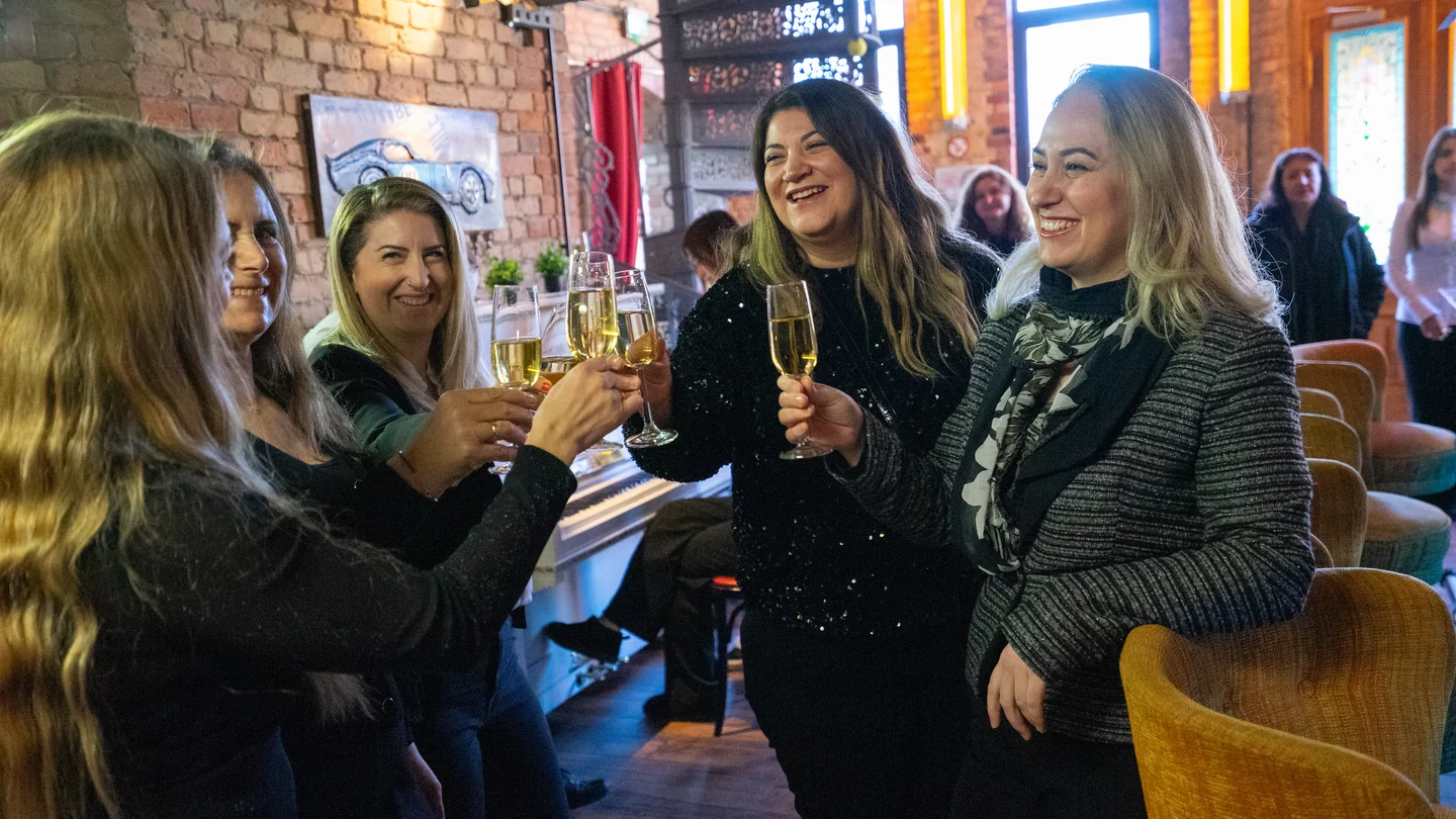 Eine Gruppe stößt mit erhobenen Gläsern an der Bar im XELOR Kesselhaus an.